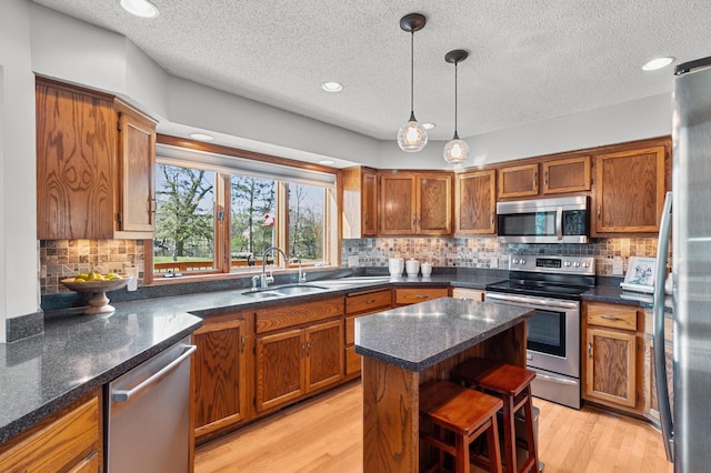 kitchen featuring a sink, pendant lighting, brown cabinetry, and stainless steel appliances