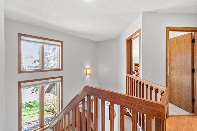 corridor featuring a textured ceiling and an upstairs landing