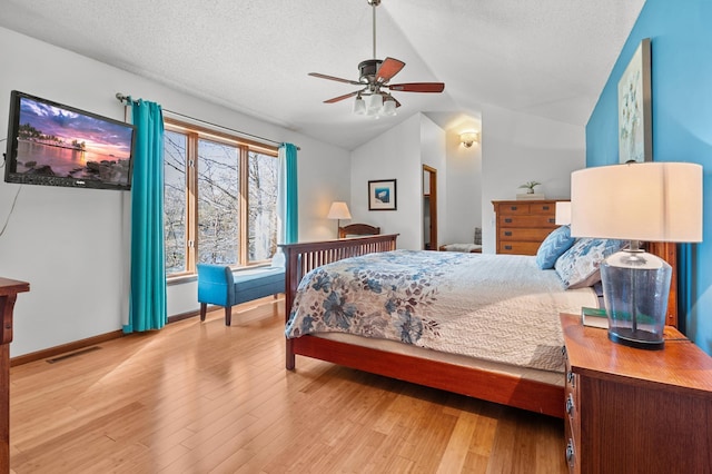 bedroom featuring a textured ceiling, visible vents, wood finished floors, and lofted ceiling