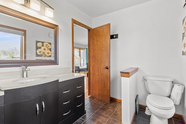 bathroom featuring vanity, tile patterned flooring, baseboards, and toilet