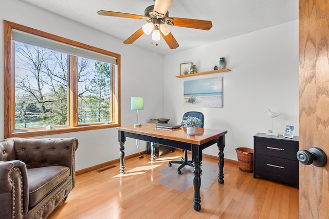 home office with baseboards, light wood-style flooring, ceiling fan, and visible vents