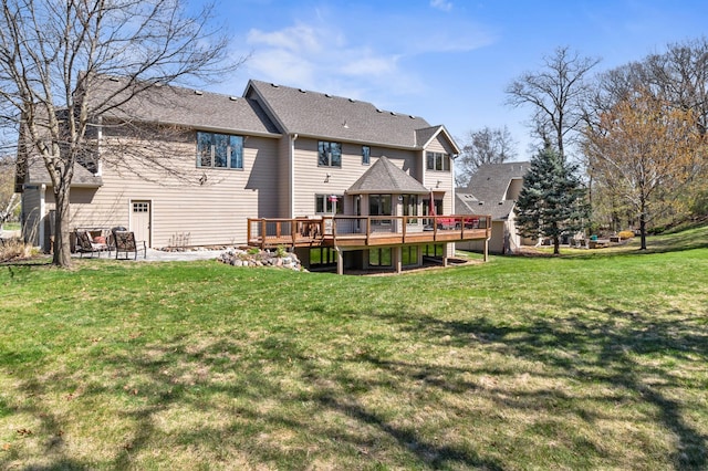 rear view of house with a yard, a wooden deck, a shingled roof, and a patio area