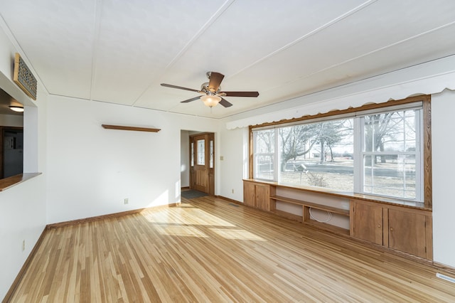 empty room featuring baseboards, built in study area, a ceiling fan, and light wood-style floors