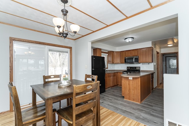 kitchen featuring a notable chandelier, a peninsula, visible vents, appliances with stainless steel finishes, and brown cabinetry