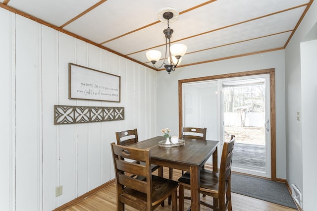 dining space with baseboards, visible vents, light wood-style flooring, and a notable chandelier