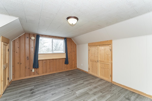 additional living space featuring lofted ceiling, baseboards, and wood finished floors