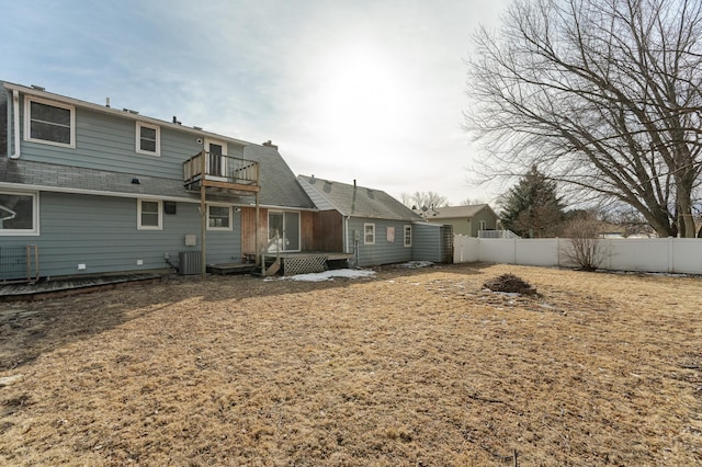 back of property with a balcony, central air condition unit, a fenced backyard, and roof with shingles