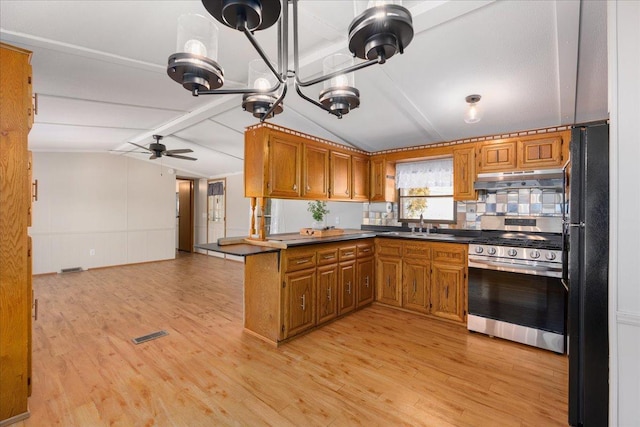 kitchen featuring brown cabinetry, stainless steel range with gas cooktop, freestanding refrigerator, and under cabinet range hood