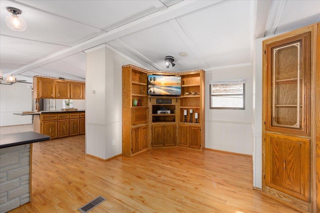 interior space with brown cabinets, a wainscoted wall, visible vents, lofted ceiling with beams, and light wood-type flooring