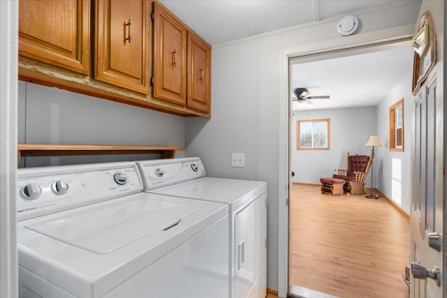 laundry area featuring wood finished floors, a ceiling fan, baseboards, independent washer and dryer, and cabinet space