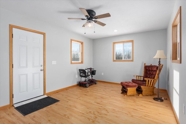 living area featuring a ceiling fan, baseboards, and wood finished floors