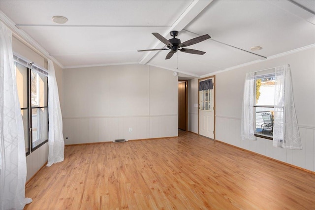 spare room featuring visible vents, a wainscoted wall, lofted ceiling with beams, ceiling fan, and light wood-style floors