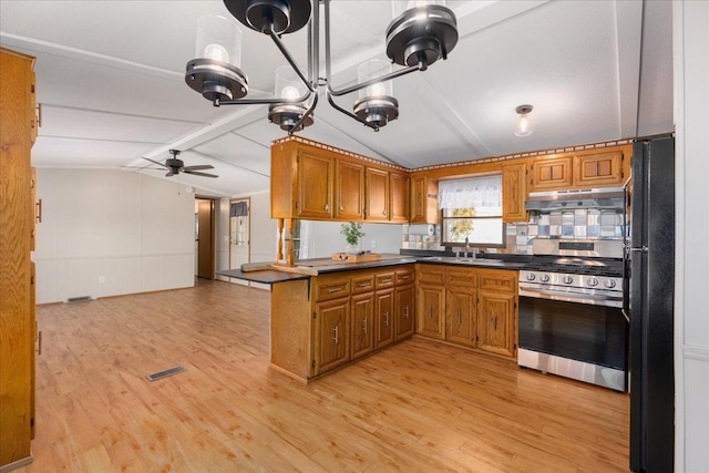 E4970 865th Ave, Sherman Twp, WI 54725 - kitchen featuring gas range, freestanding refrigerator, under cabinet range hood, and brown cabinets