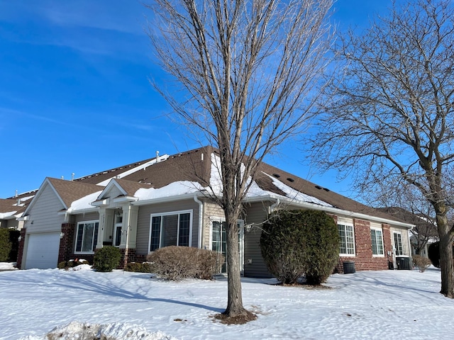 view of front of property featuring brick siding, an attached garage, and central AC unit