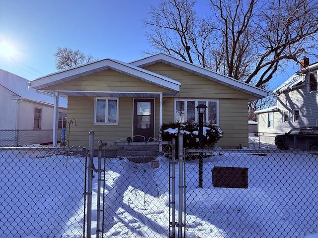 bungalow with a fenced front yard and a gate