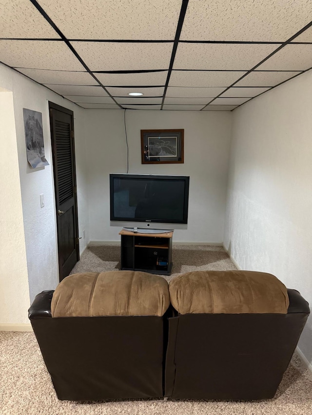 carpeted living room featuring baseboards and a drop ceiling