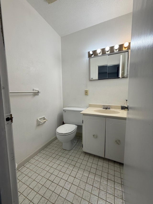 bathroom featuring tile patterned flooring, vanity, toilet, a textured ceiling, and baseboards