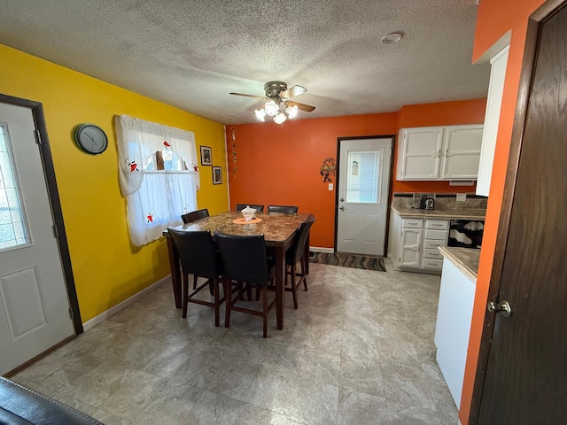 dining room featuring baseboards, a ceiling fan, and a textured ceiling