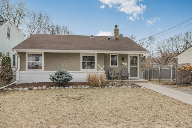 back of house featuring brick siding, a shingled roof, a chimney, fence, and stucco siding