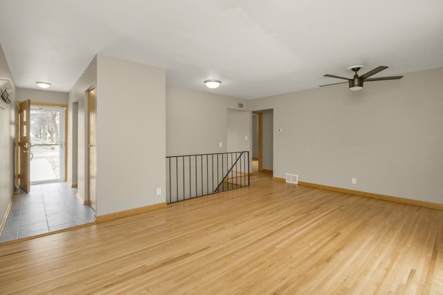 unfurnished room with ceiling fan, light wood-type flooring, visible vents, and baseboards