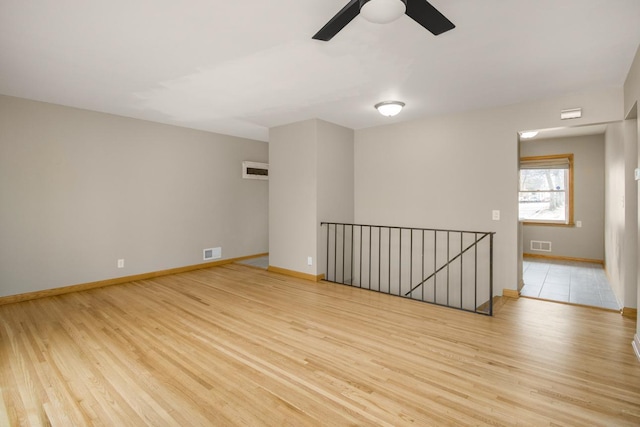 unfurnished room with light wood finished floors, baseboards, and visible vents