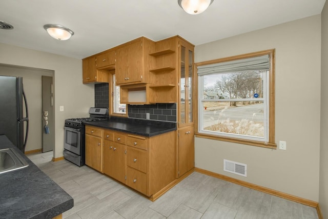 kitchen featuring visible vents, freestanding refrigerator, open shelves, tasteful backsplash, and gas stove