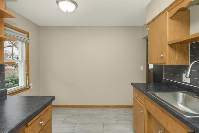 kitchen with a sink, baseboards, backsplash, open shelves, and dark countertops