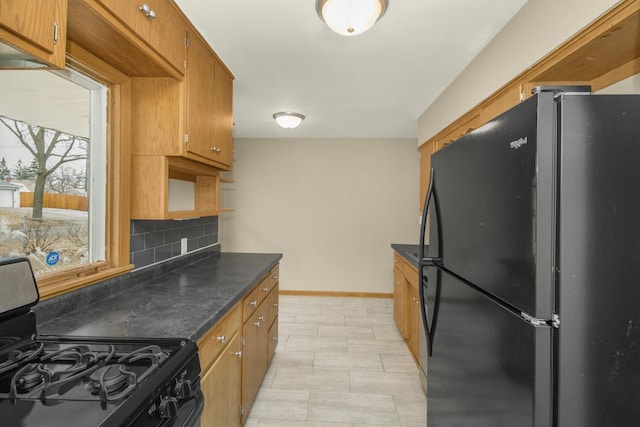 kitchen featuring tasteful backsplash, baseboards, brown cabinetry, dark countertops, and black appliances