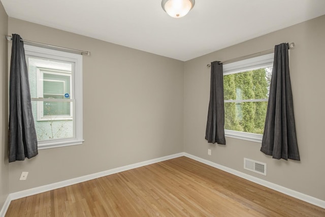 spare room featuring visible vents, light wood finished floors, and baseboards