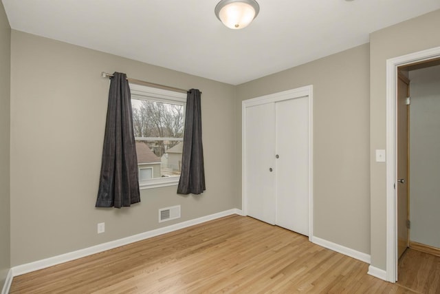 unfurnished bedroom featuring a closet, visible vents, light wood-style flooring, and baseboards