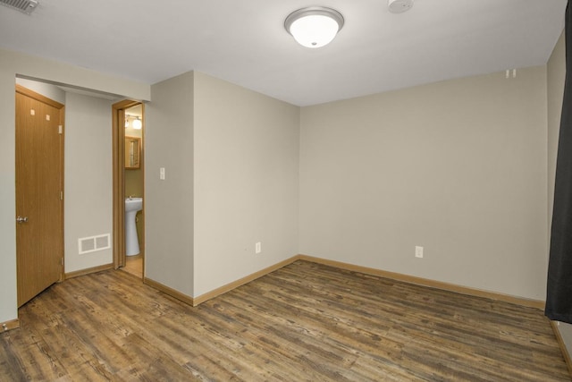 spare room featuring baseboards, visible vents, and wood finished floors