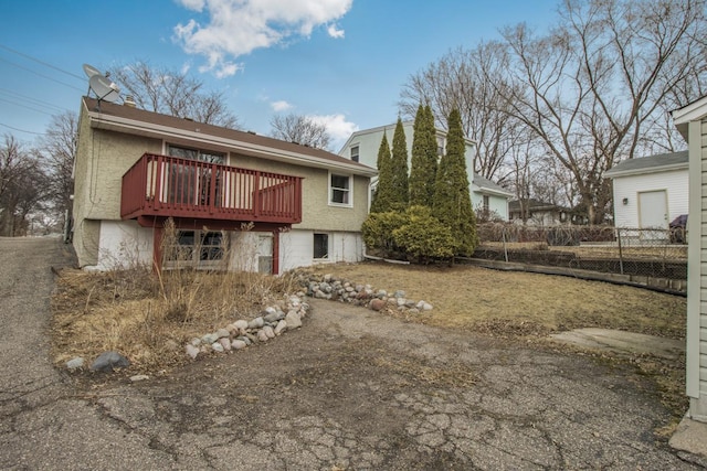 rear view of property with aphalt driveway, fence, and a wooden deck