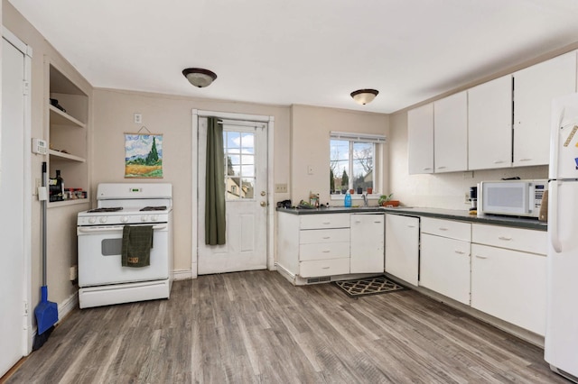 kitchen with white appliances, wood finished floors, white cabinetry, open shelves, and dark countertops