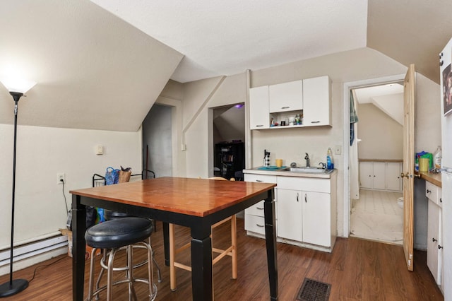 kitchen featuring dark wood-style flooring, light countertops, visible vents, white cabinetry, and a sink