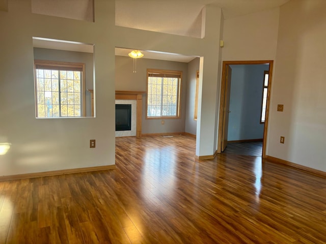 unfurnished living room featuring a wealth of natural light, a tile fireplace, and wood finished floors