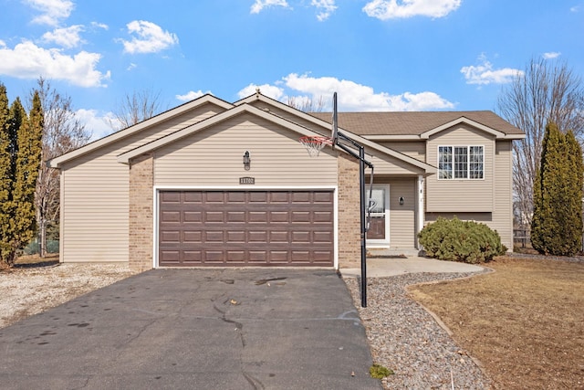 split level home featuring driveway, brick siding, and an attached garage