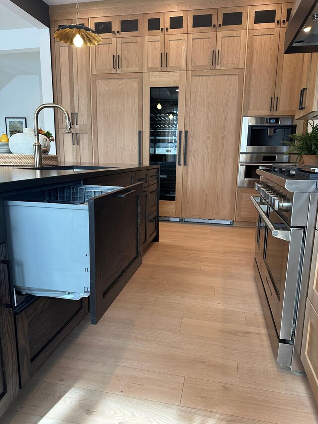 kitchen with wine cooler, appliances with stainless steel finishes, glass insert cabinets, light wood-style floors, and under cabinet range hood