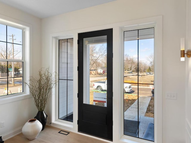 doorway to outside featuring plenty of natural light, wood finished floors, and baseboards