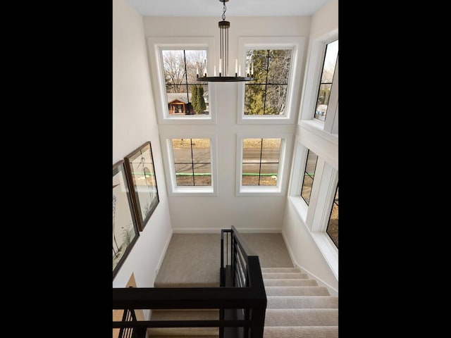 stairway with a chandelier, baseboards, carpet flooring, and a healthy amount of sunlight