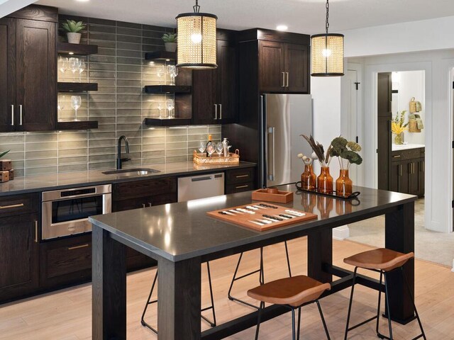 kitchen with a sink, appliances with stainless steel finishes, open shelves, tasteful backsplash, and dark countertops