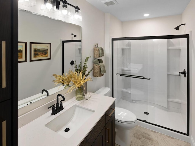 bathroom featuring visible vents, a shower stall, toilet, and vanity