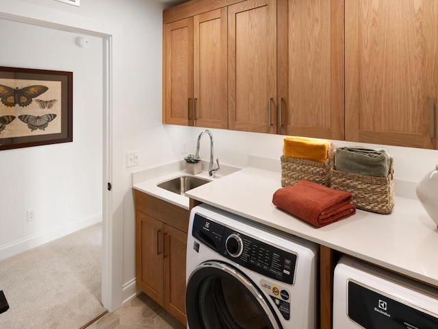 washroom featuring washer / clothes dryer, cabinet space, a sink, and baseboards