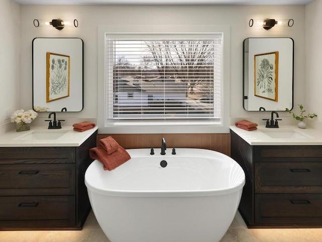 full bathroom featuring two vanities, a healthy amount of sunlight, and a sink