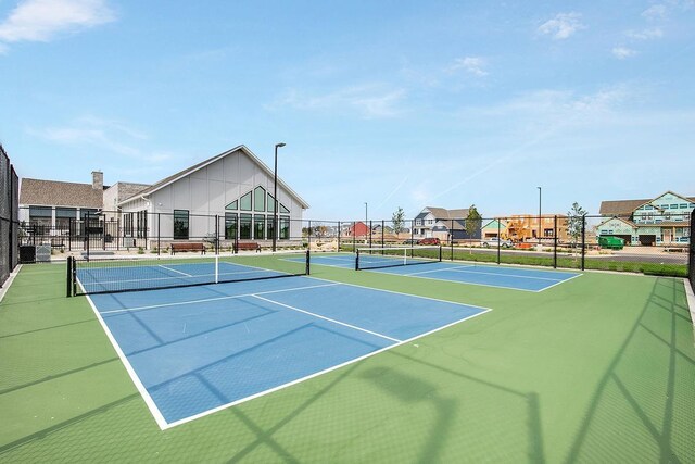 view of tennis court featuring a residential view and fence