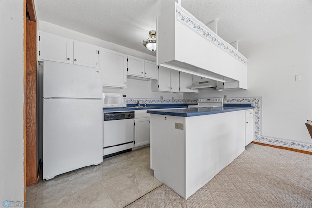 kitchen featuring white appliances, dark countertops, white cabinetry, and under cabinet range hood