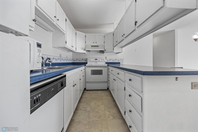 kitchen with under cabinet range hood, white appliances, a sink, white cabinetry, and dark countertops