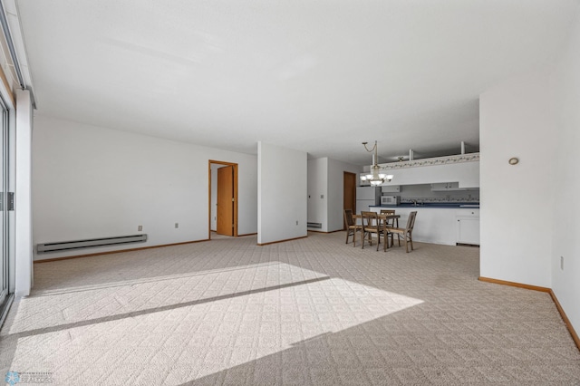 unfurnished living room with a chandelier, baseboard heating, baseboards, and light colored carpet