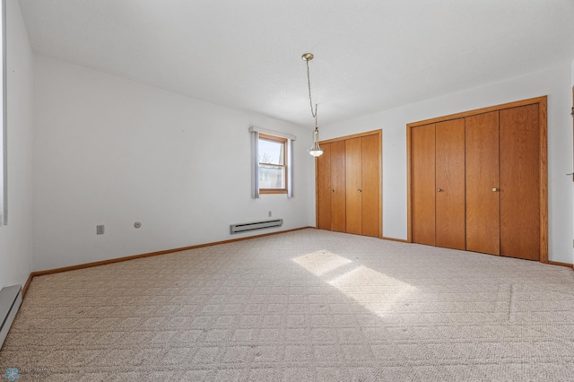 unfurnished bedroom with two closets, light colored carpet, baseboard heating, a baseboard heating unit, and baseboards