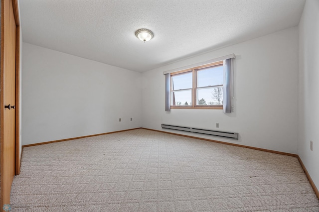 spare room featuring a baseboard radiator, light colored carpet, a textured ceiling, and baseboards