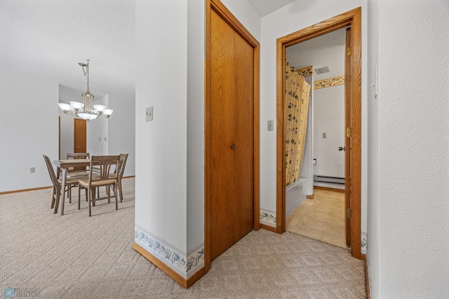 hallway with light carpet, an inviting chandelier, a baseboard radiator, and baseboards